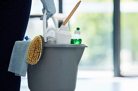 One unknown mixed race woman holding cleaning supplies while cleaning her apartment. An unrecognizable domestic cleaner wearing latex cleaning gloves with a collection of cleaning products, a Photo by Peopleimages.com