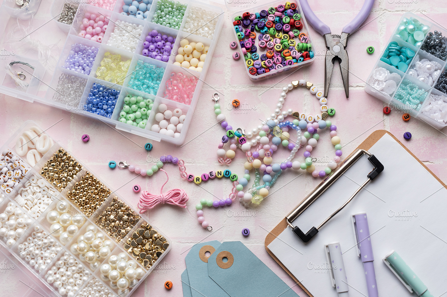 Colorful beads and jewelry making supplies arranged on pink tile, an Arts & Entertainment Photo by Olena Rudo