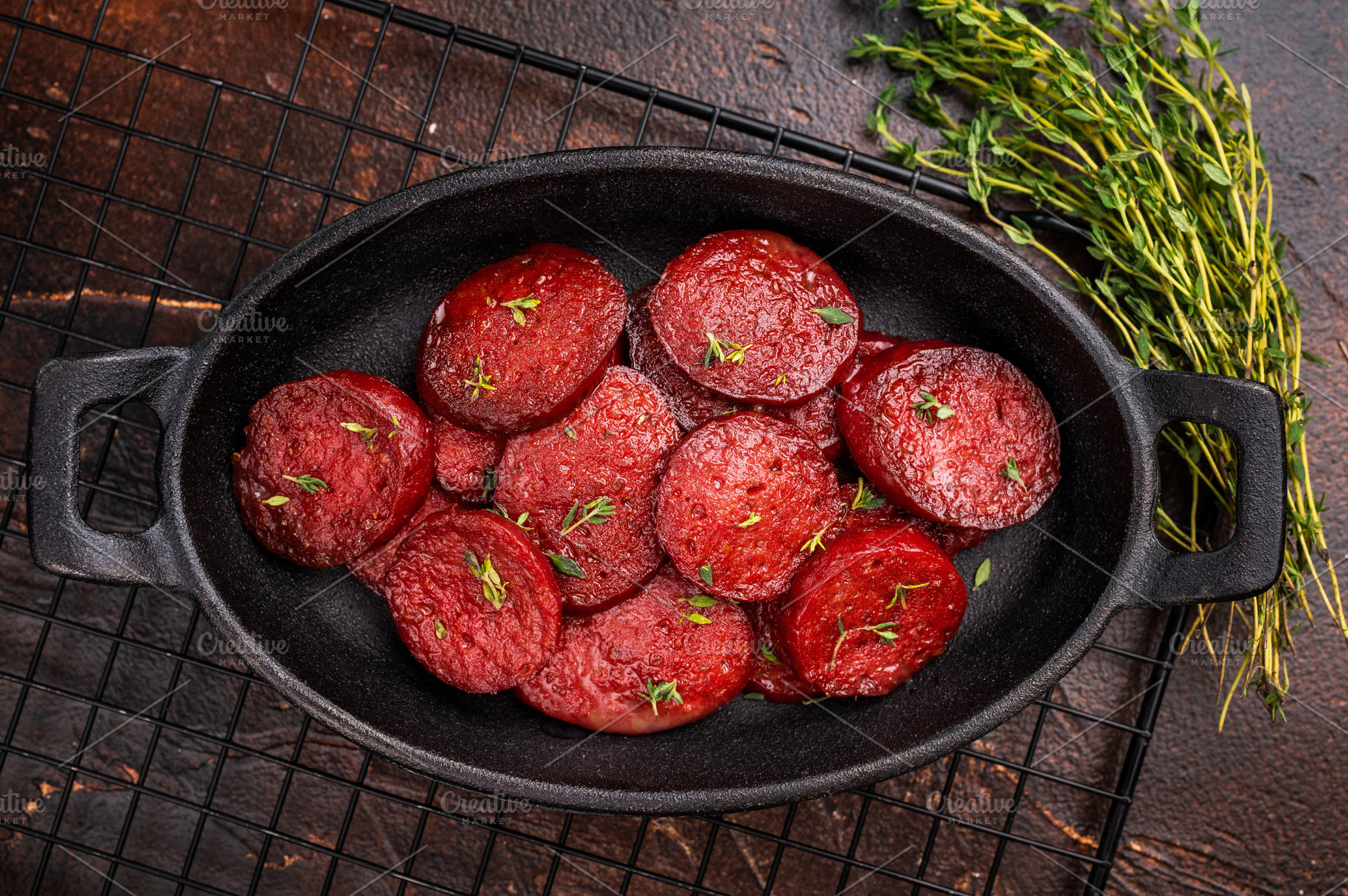 Fried Turkish sucuk (sujuk) slices in a cast iron pan with thyme, a Photo by composter-box@mail.ru