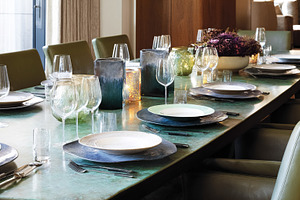 Long dining table elegantly set with plates, glasses, silverware, a Photo by Studio ANNA
