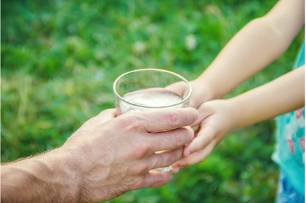 The father gives the child a glass, a Food & Drink Photo by yanadjana
