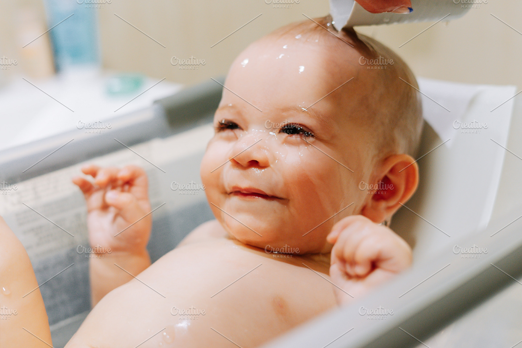 Portrait of a nine month old baby taking a bath with water running trough his f, a Person Photo by rubenchase