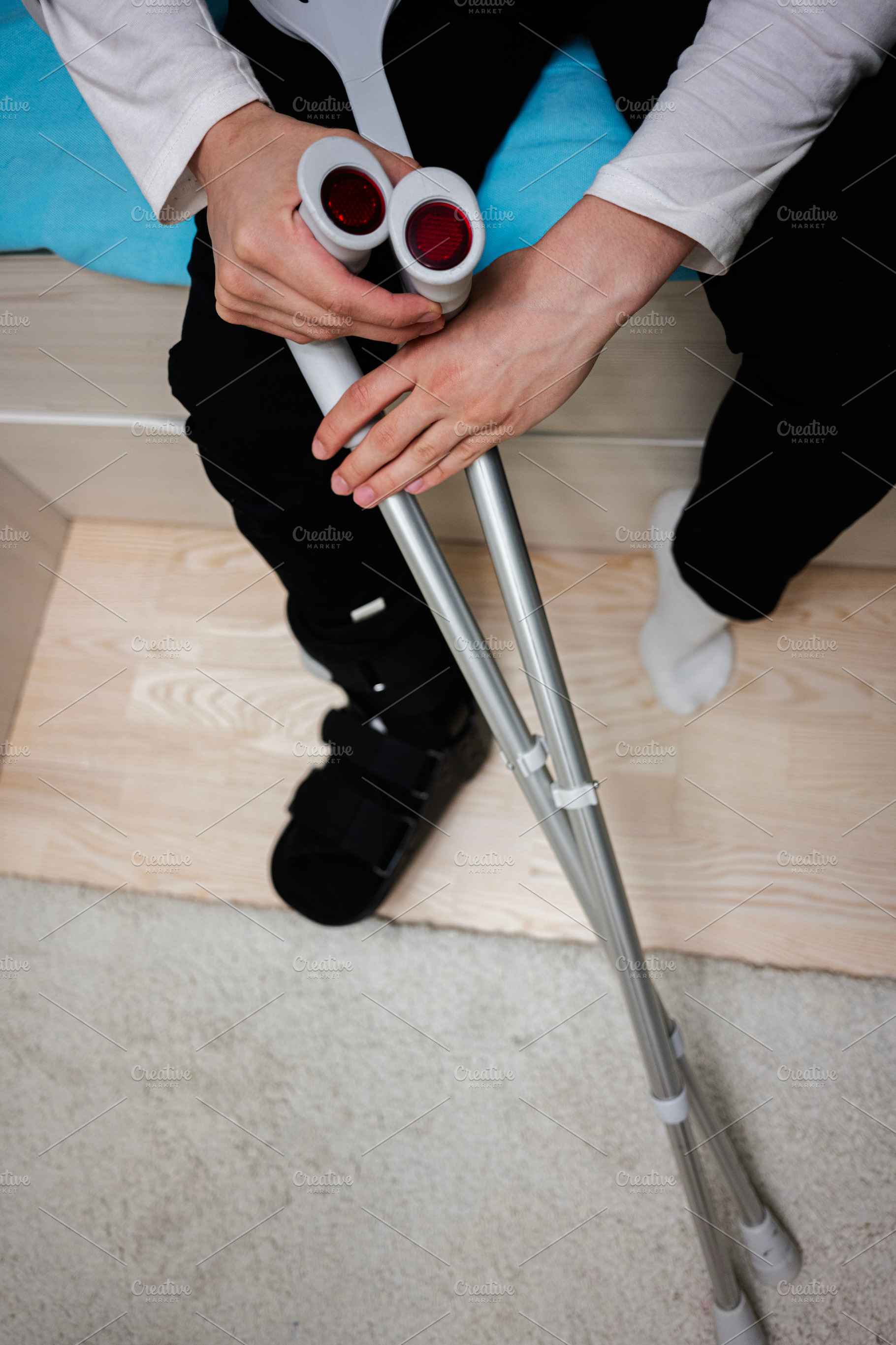 Person resting on bed with crutches and a medical boot on leg, a Health & Medical Photo by AS photostudio