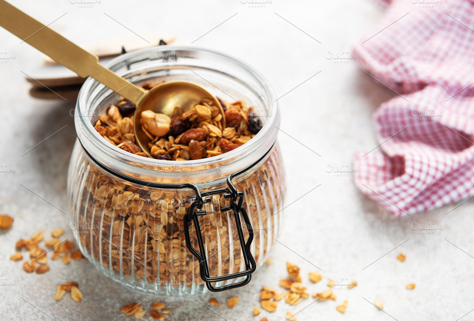 Granola cereal with nuts in a glass jar and spoon, healthy break, a Food & Drink Photo by Olena Rudo