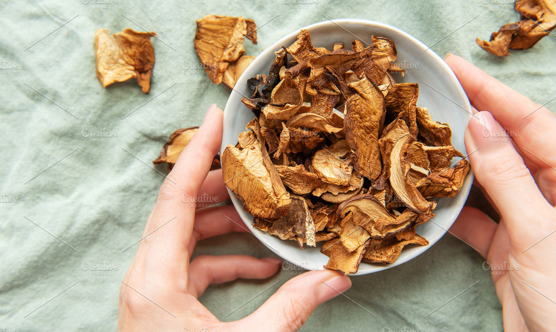 Chef holding bowl of dried mushrooms on green tablecloth, a Food & Drink Photo by Olena Rudo