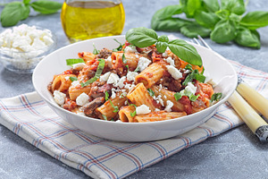 Rigatoni alla Norma pasta with eggplant and tomato, served with basil and ricot, a Food & Drink Photo by iuliia_n