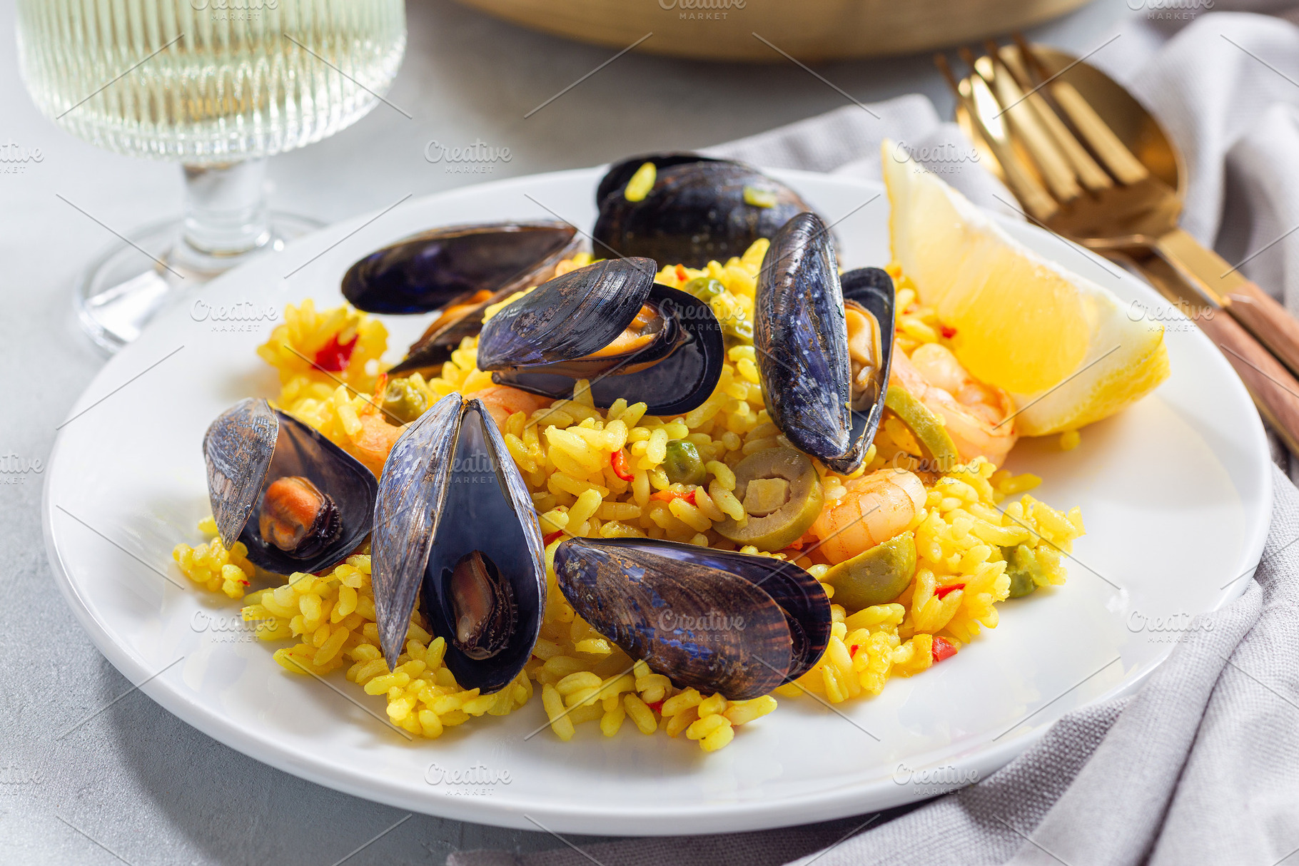 Seafood paella with mussels and shrimps, on white plate, with lemon and white w, a Food & Drink Photo by iuliia_n