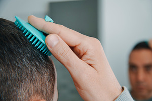 man combs his hair in the bathroom, a Photo by Nito