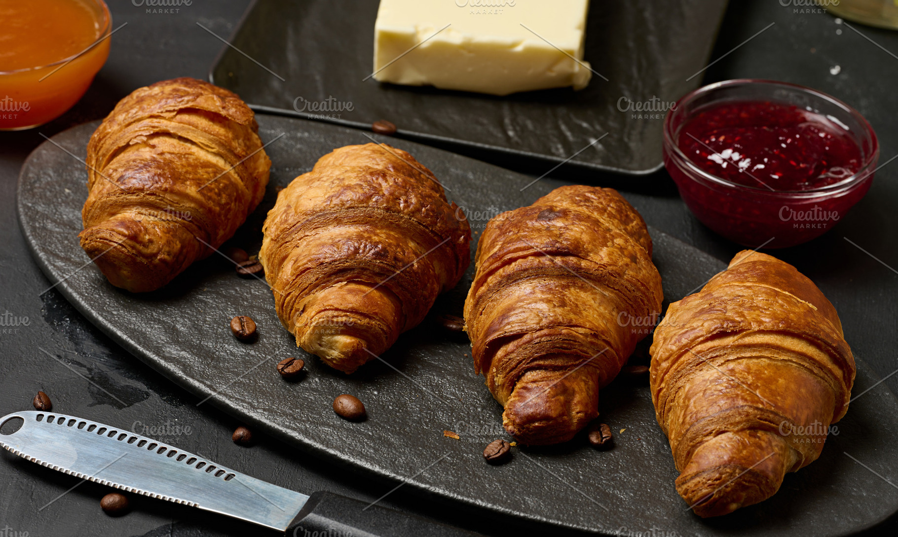 Golden croissants laid out in a row on a dark stone board, surro, a Food & Drink Photo by ndanko