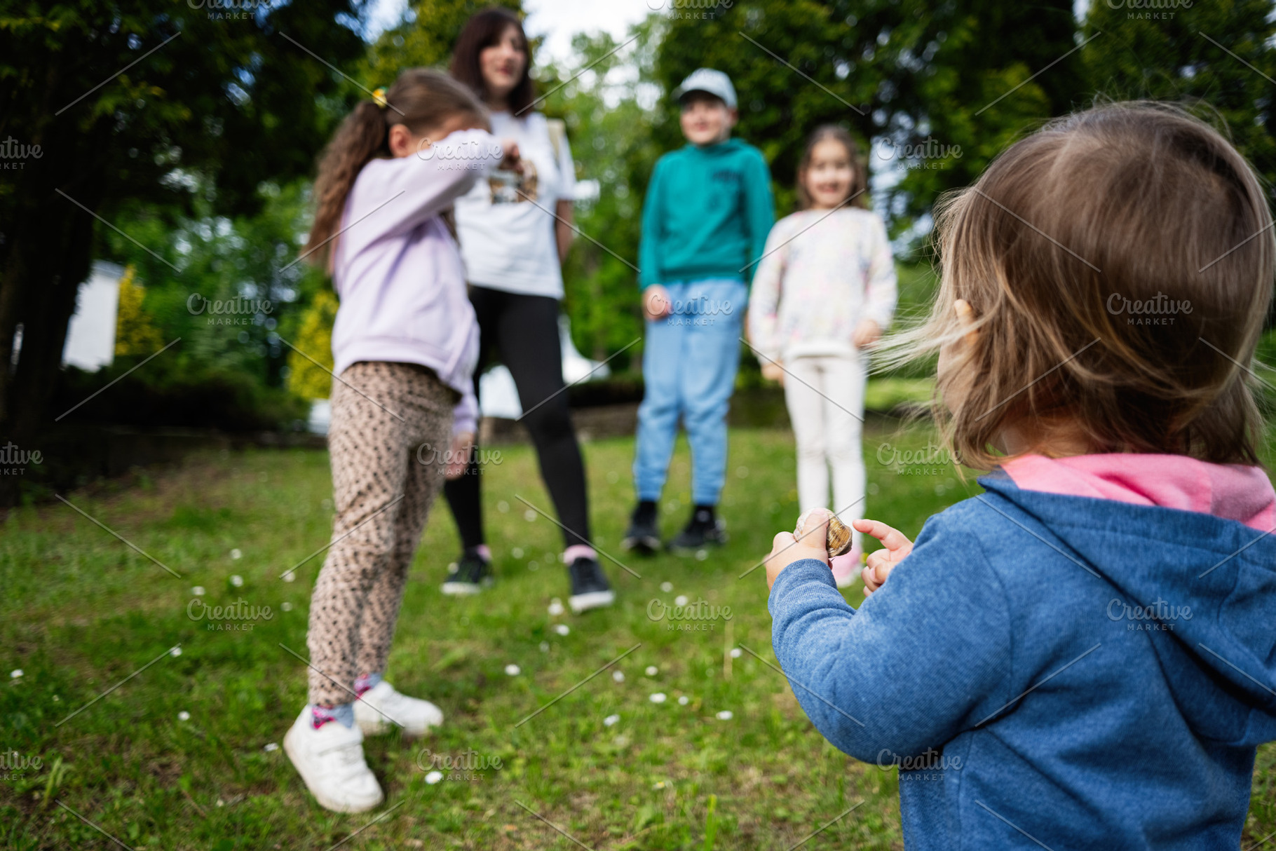 Children playing outdoors in a grassy park area during a sunny day, a Photo by AS photostudio
