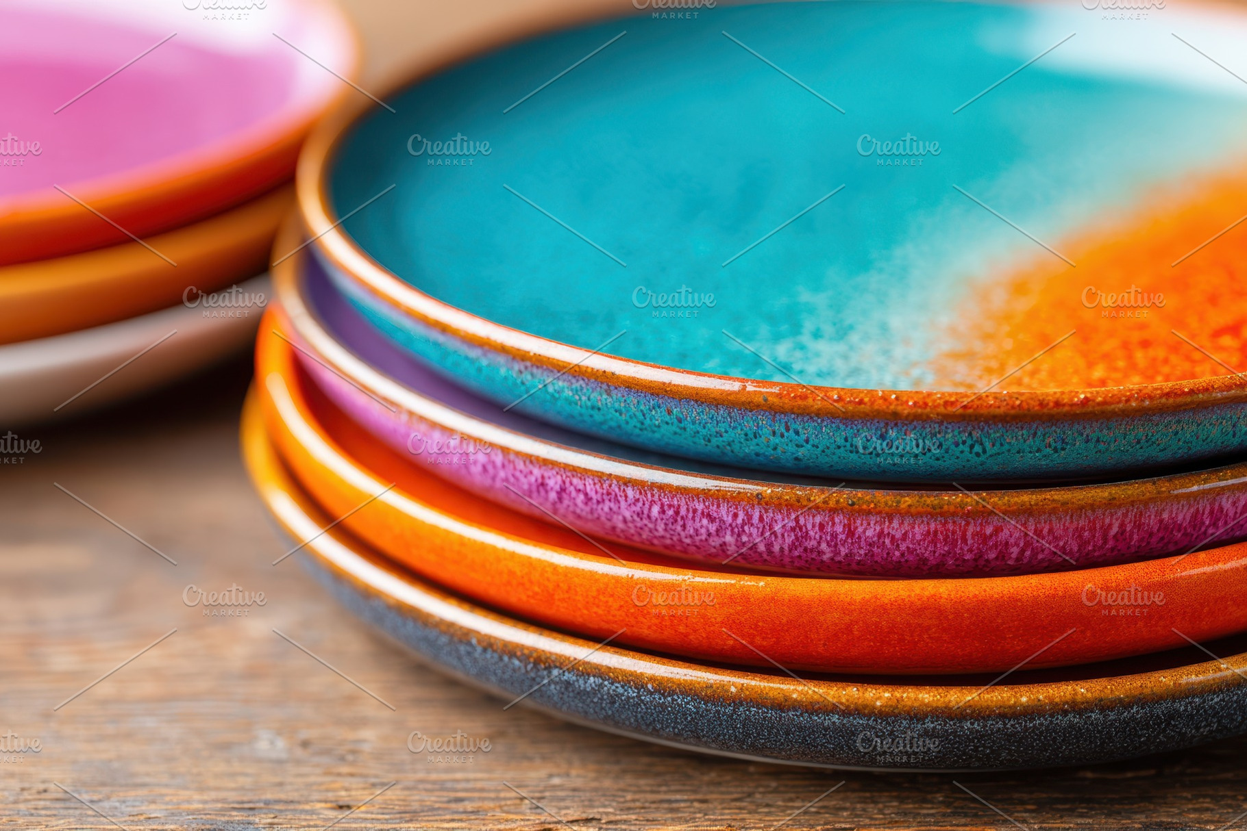 Stack of colorful glazed ceramic plates on wooden table, a Food & Drink Photo by AlyaAnd