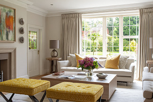 Elegant living room with cozy sofas, yellow ottomans, and firepl, a Photo by Studio ANNA