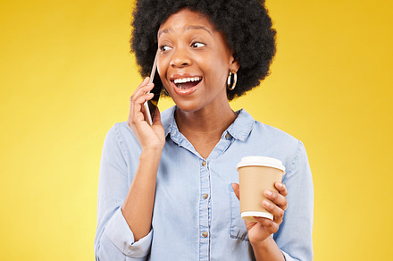 Phone call, happy and black woman with coffee in studio, smile and listening on yellow background. Smartphone, conversation and girl with tea surprised, joke and humor while enjoying speaking online, a Photo by Peopleimages.com