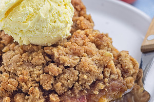 Delicious Peach Crisp or cobbler on plate with scoop of vanilla ice cream, vert, a Food & Drink Photo by iuliia_n