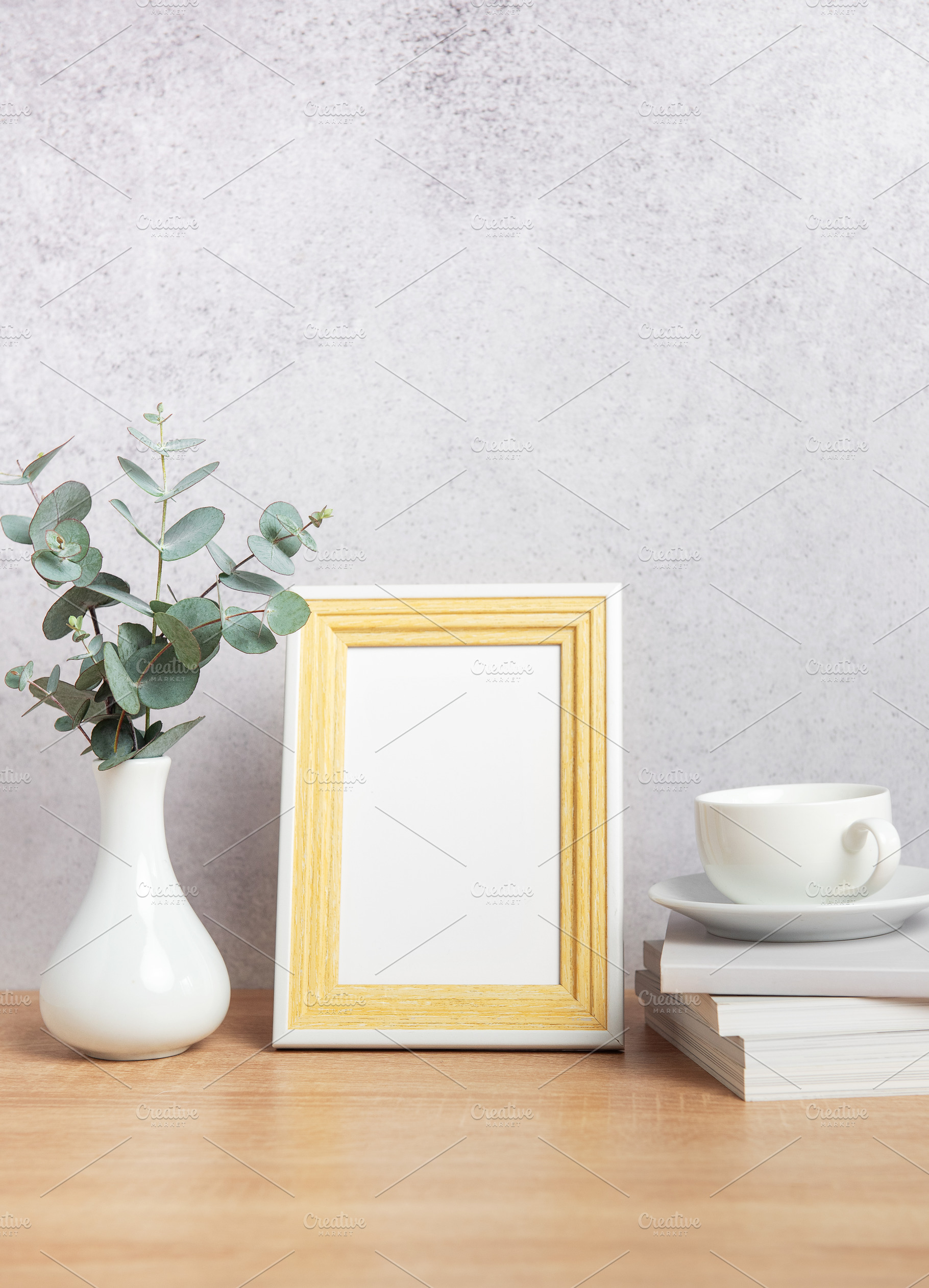 Empty photo frame, eucalyptus leaves, books and coffee cup on ta, a Background Photo by Olena Rudo