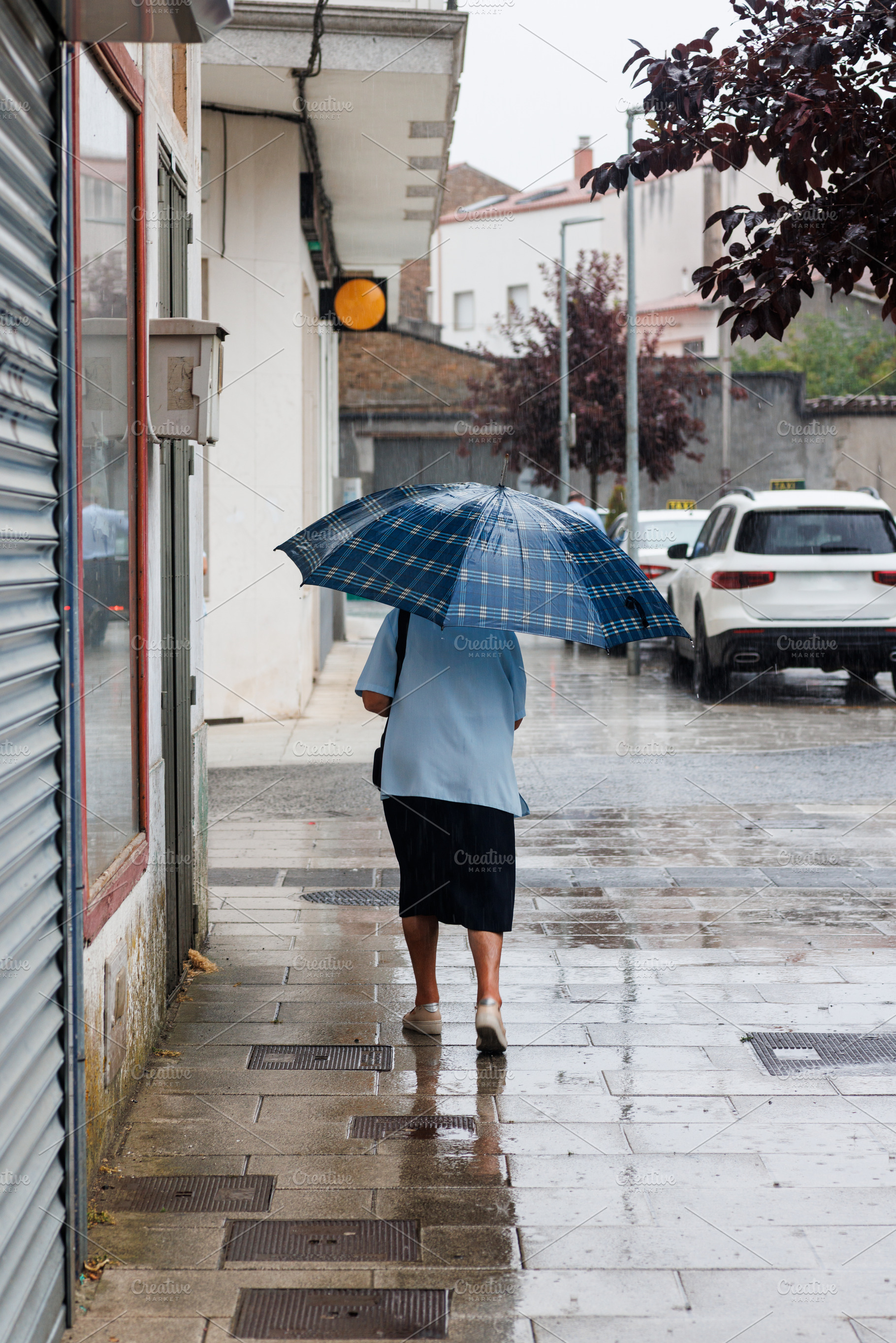 An elderly lady with Umbrella Walking on Rainy Street, Melide, S, a Person Photo by Bepslabor