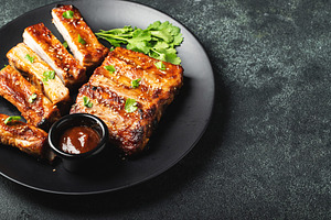 Hot grilled spare ribs from a summer BBQ served on a plate with sauce. Top view, a Food & Drink Photo by Budarinphoto