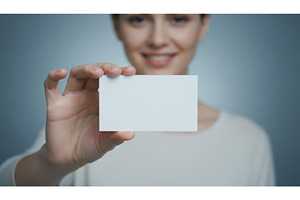 Smiling woman holding blank white, a Business Photo by Igor Tichonow