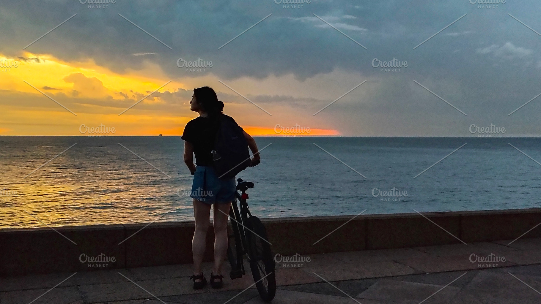 Woman watching the sunset over the ocean in peaceful silence, a Person Photo by DanFLCreativo