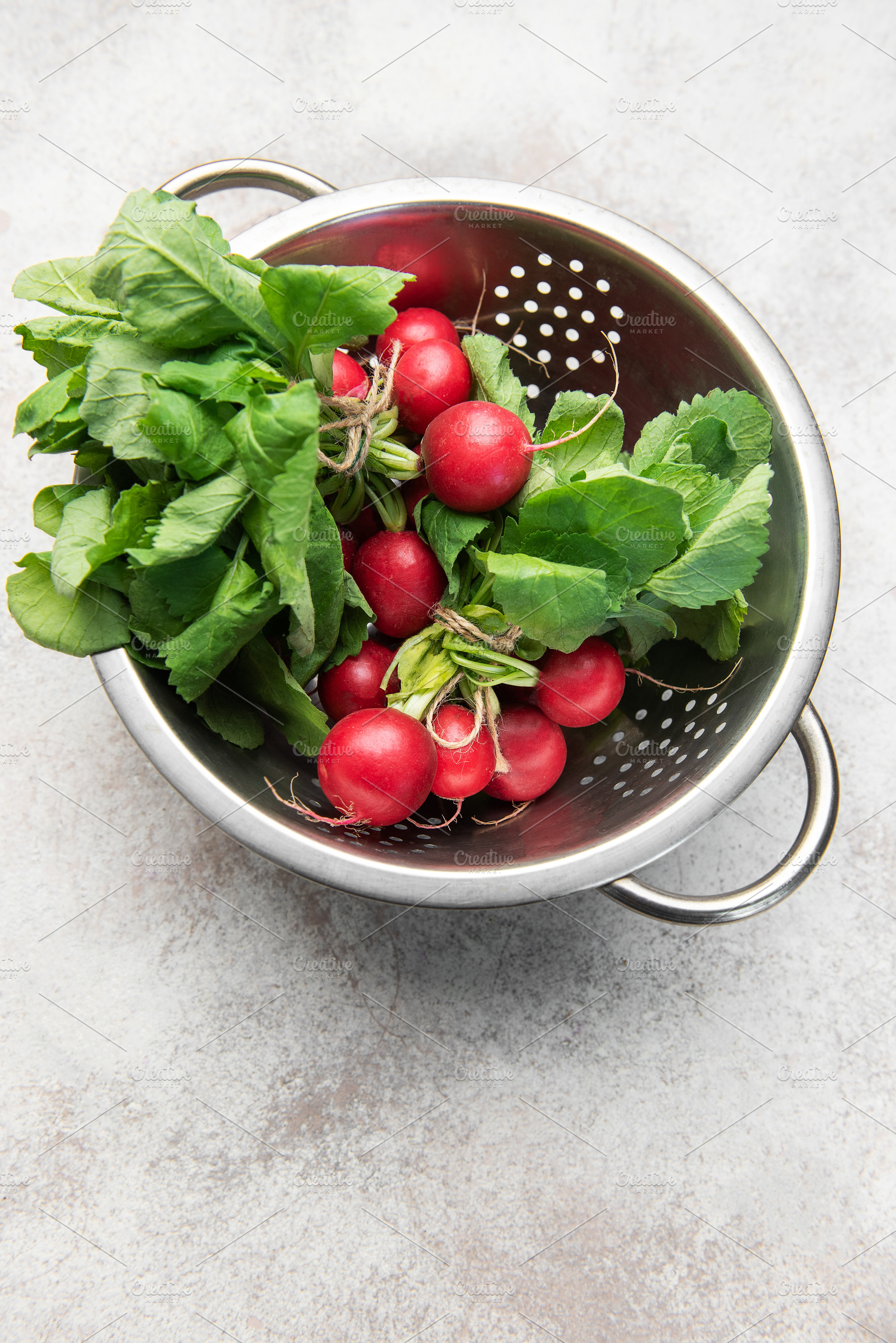 Fresh radishes with green tops in colander, a Food & Drink Photo by Olena Rudo