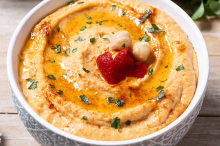 Roasted red pepper hummus in white bowl on wooden table, a Food & Drink Photo by etorres69