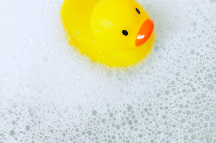 Bathtub with foam bubbles and yellow playful rubber duck in bubb