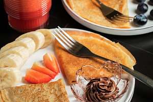 A plate of crepes filled with chocolate spread and topped with banana slices an, a Food & Drink Photo by Budarinphoto