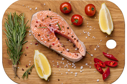 Raw salmon steak on a wooden cutting board, lemon slices, spices, a Food & Drink Photo by ndanko