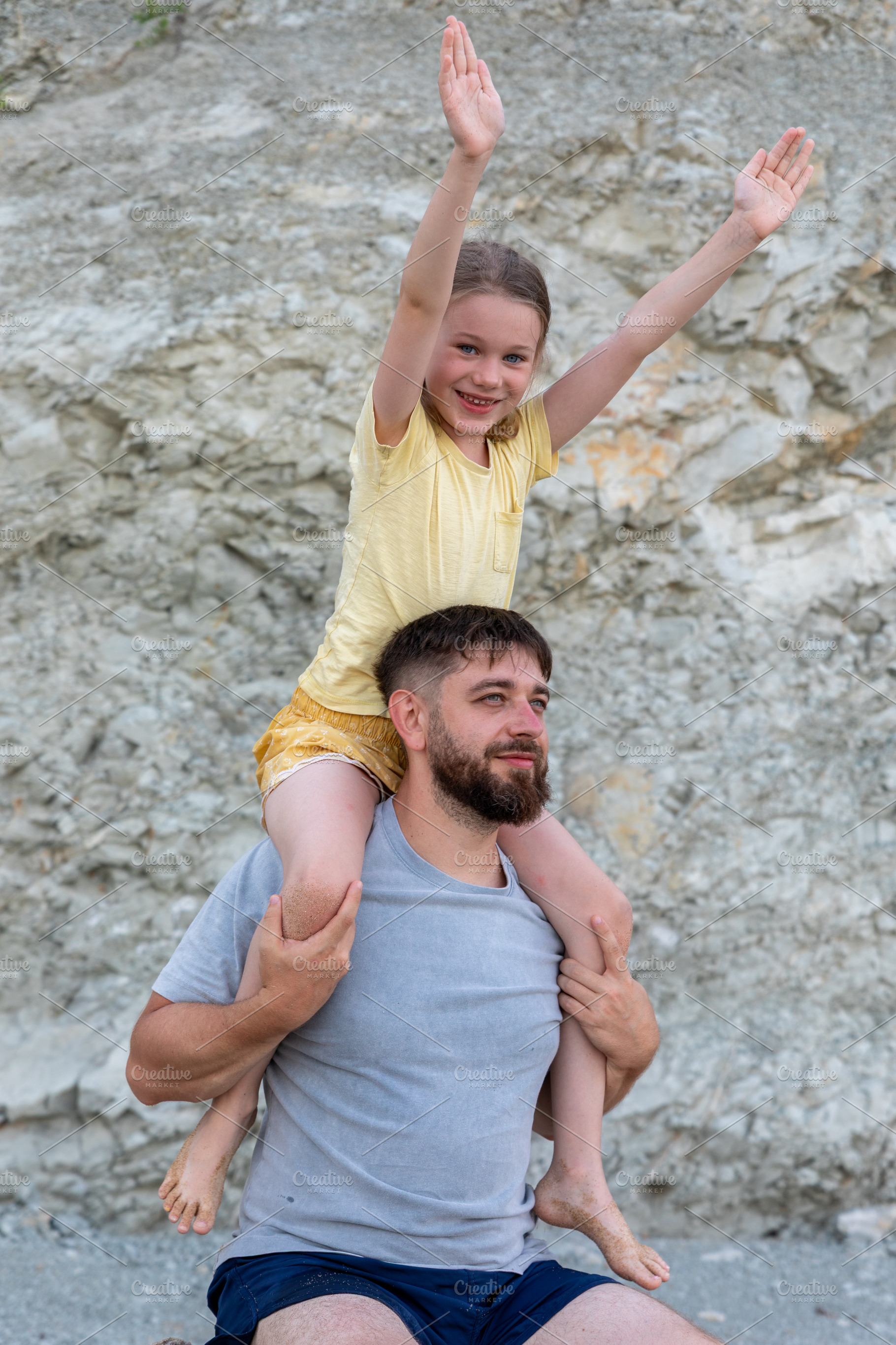 Smiling father carries young daughter on shoulders outdoors, both looking happy, a Person Photo by Ales Munt