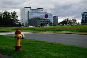 Urban scene in Reykjavik with a hydrant and modern building under cloudy skies, a Photo by AS photostudio