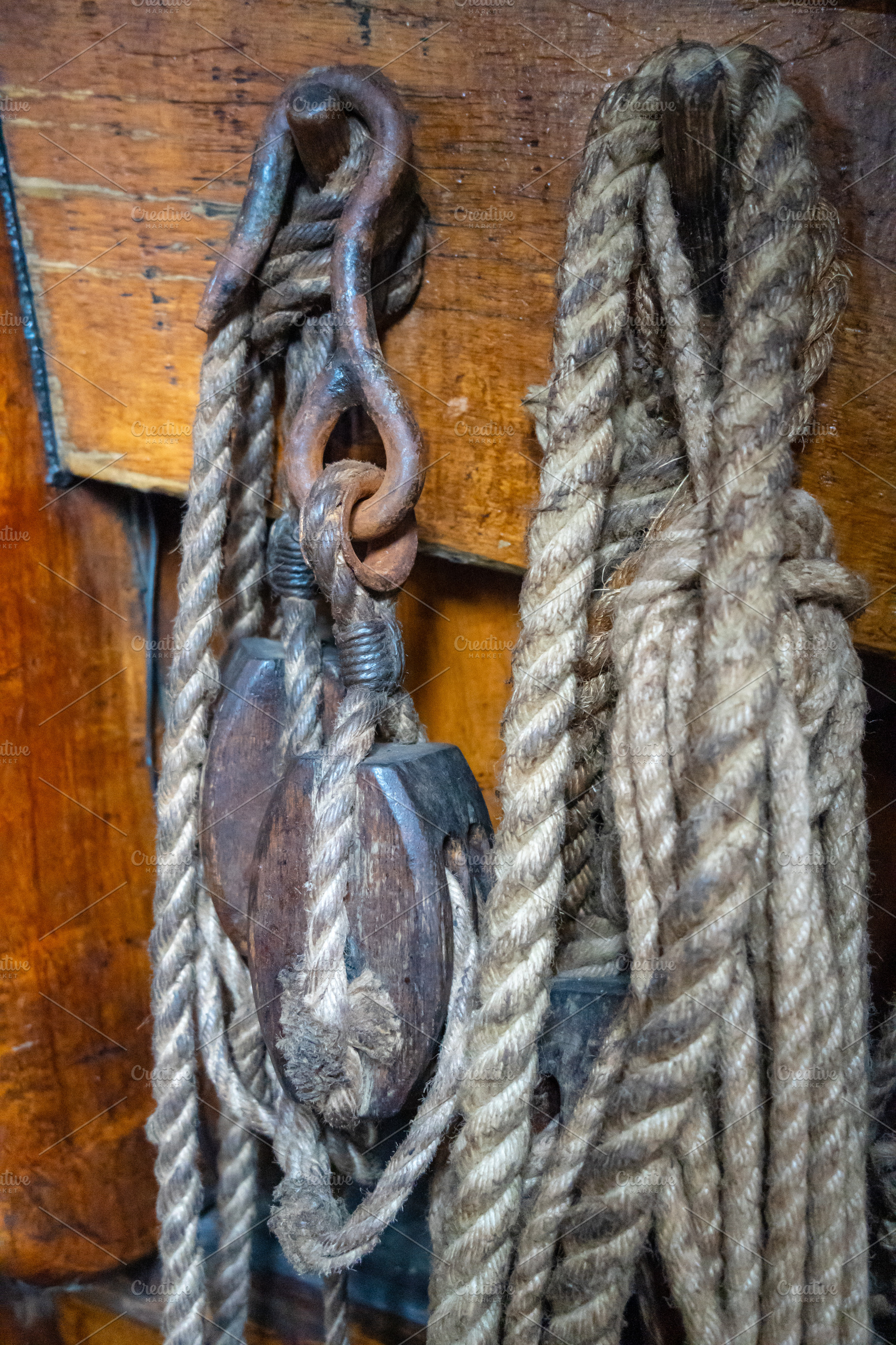 Old sailing ship ropes and wooden pulleys on a historic vessel, an Abstract Photo by GoodGoods