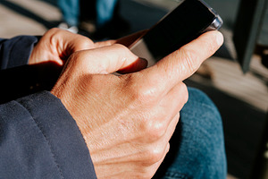 a man uses a smartphone while seated outdoors, a Photo by Nito