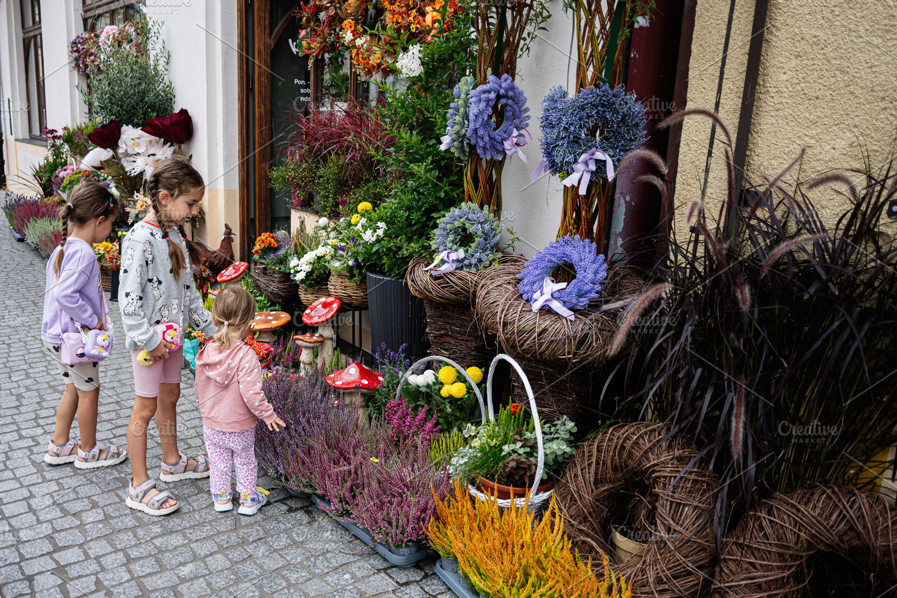 Children admiring colorful flowers outside a shop in Rzeszow, Poland, a Photo by AS photostudio