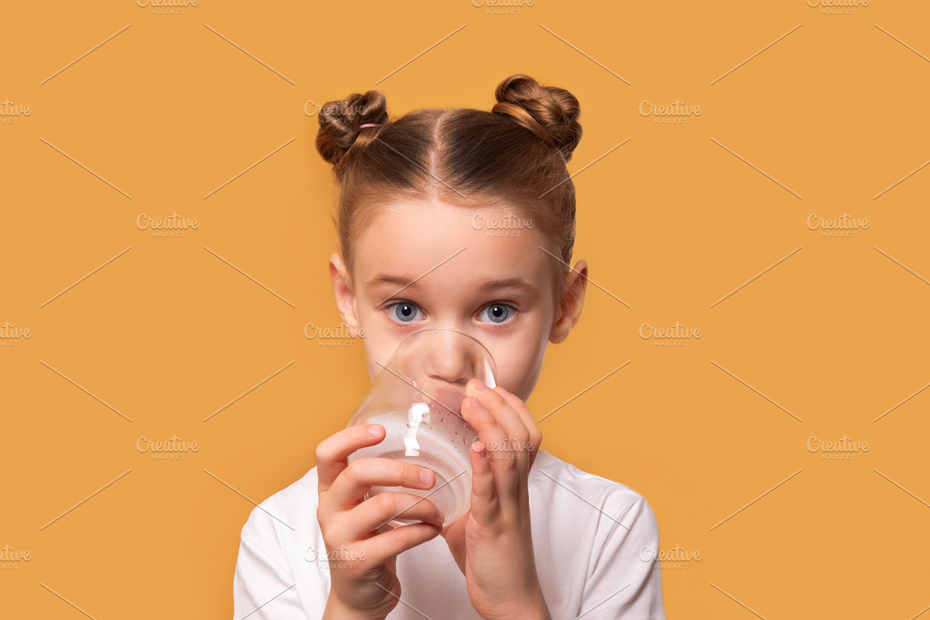 Young girl with brown hair in buns drinks water from a glass, lo, a Person Photo by Ales Munt