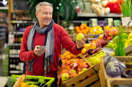 Smiling man using cell phone while shopping at supermarket, a Person Photo by Prostock-Studio