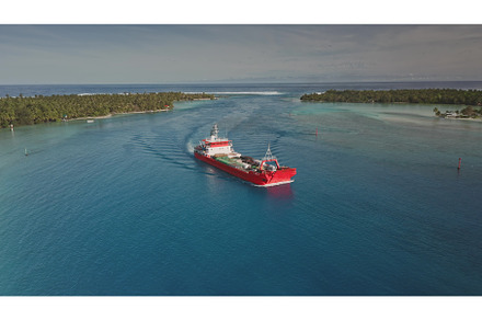 Red cargo ship navigating a narrow