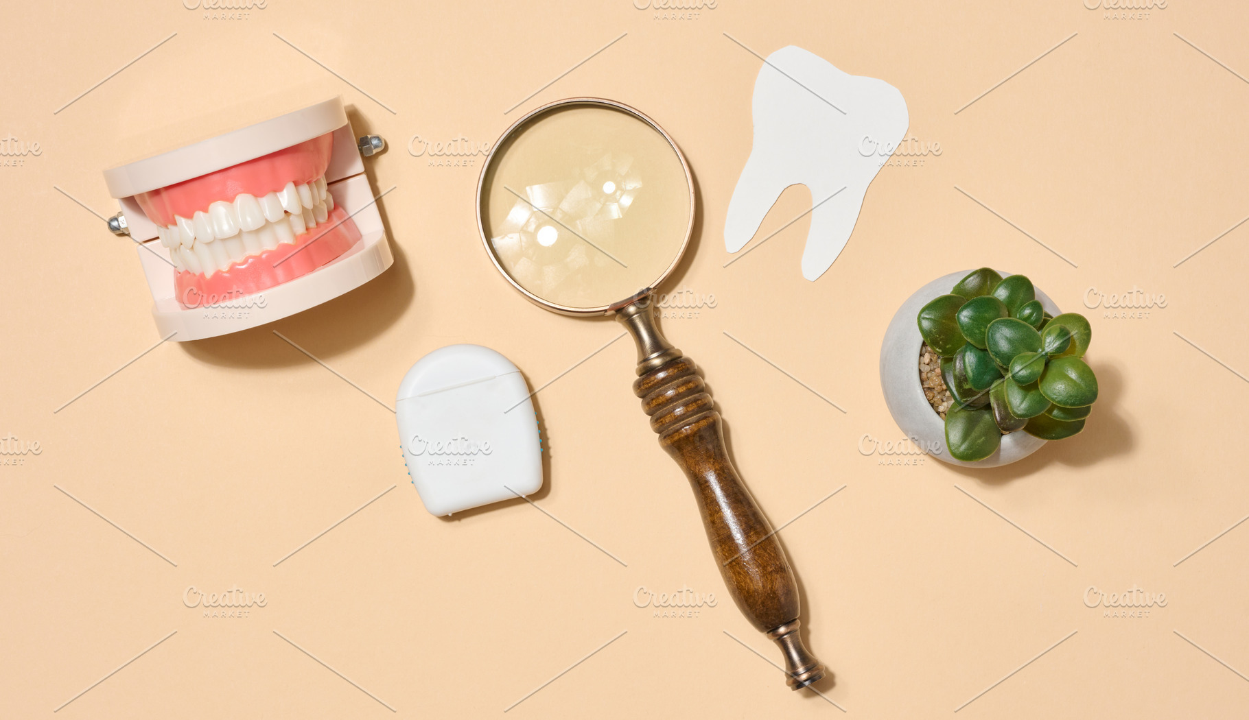 Model of dentures, magnifying glass located on beige background., a Health & Medical Photo by ndanko