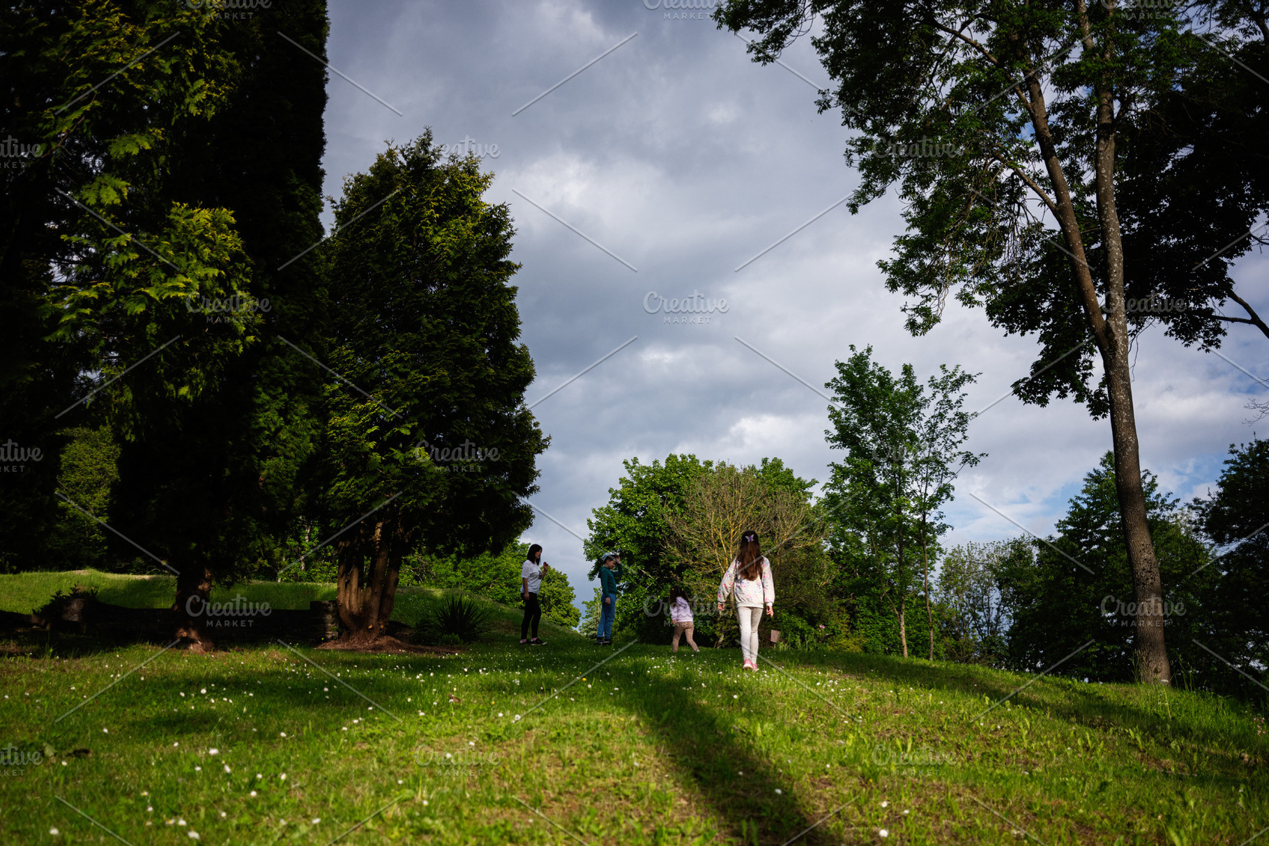 Family enjoying a scenic walk in nature surrounded by green grass and trees, a Person Photo by AS photostudio