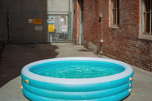 Kid’s inflatable pool in urban alley, a Sports & Recreation Photo by Virgo Studio