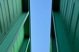 A low-angle view of two green containers against a clear blue sky, an Industrial Photo by Textures & Backgrounds