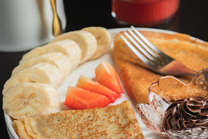 A plate of crepes filled with chocolate spread and topped with banana slices an, a Food & Drink Photo by Budarinphoto