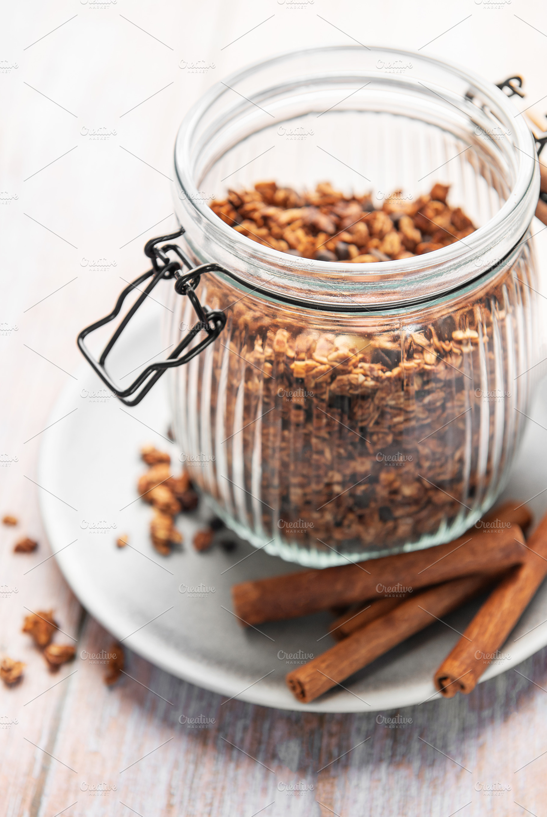 Granola cereal in glass jar with cinnamon sticks, a Food & Drink Photo by Olena Rudo