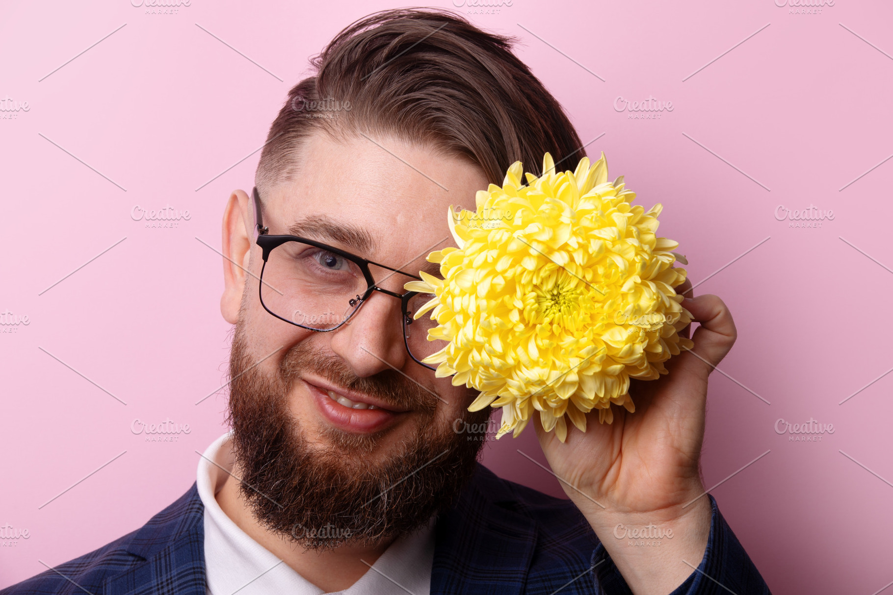 Cheerful bearded man in glasses holding a bright yellow flower n, a Person Photo by Ales Munt