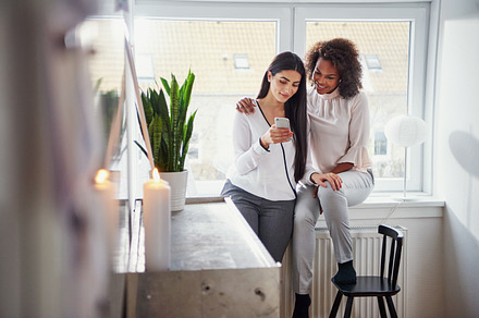 Two pretty young multiracial women browsing�smartphone, a Person Photo by Stefan & Janni