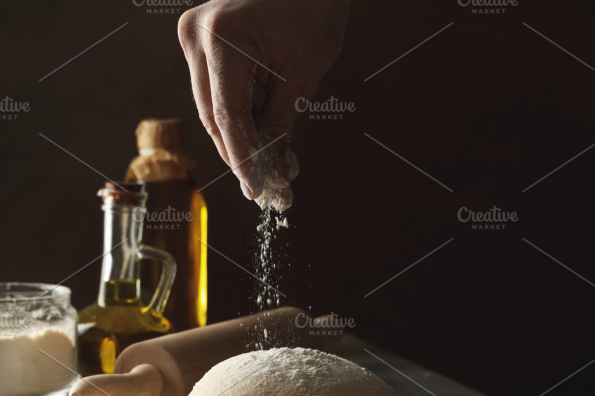 Man sprinkle flour on dough against dark background, a Food & Drink Photo by AtlasStudio PRO (Photo 1 of 4)