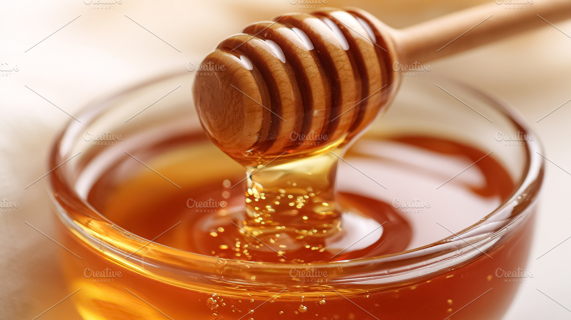 Golden honey dripping from a wooden dipper into a clear glass bo, a Photo by Studio ANNA