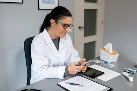 Female doctor using mobile while working, a Health & Medical Photo by davidpereiras