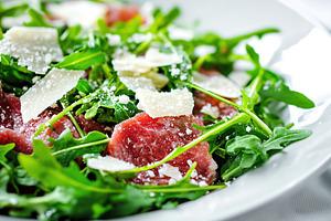 Delicious beef carpaccio served with fresh arugula and shaved cheese garnishes, a Food & Drink Photo by AlyaAnd