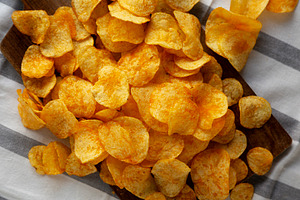 Homemade Flavored Cheese Potato Chips on a Wooden Board, top vie, a Food & Drink Photo by LiudmylaChuhunova