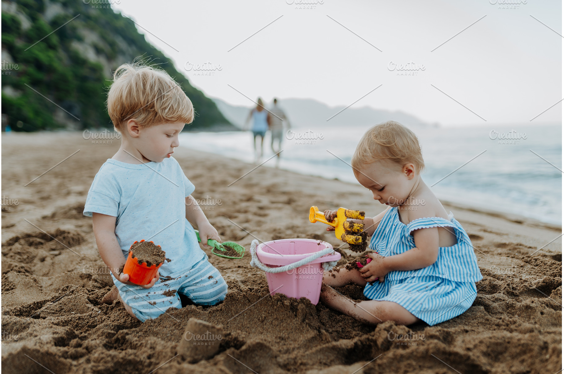 Two toddler children playing on sand, a Person Photo by HalfPoint